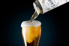 Cerveja sendo servida diretamente da lata em copo — pour clássico com colarinho generoso.